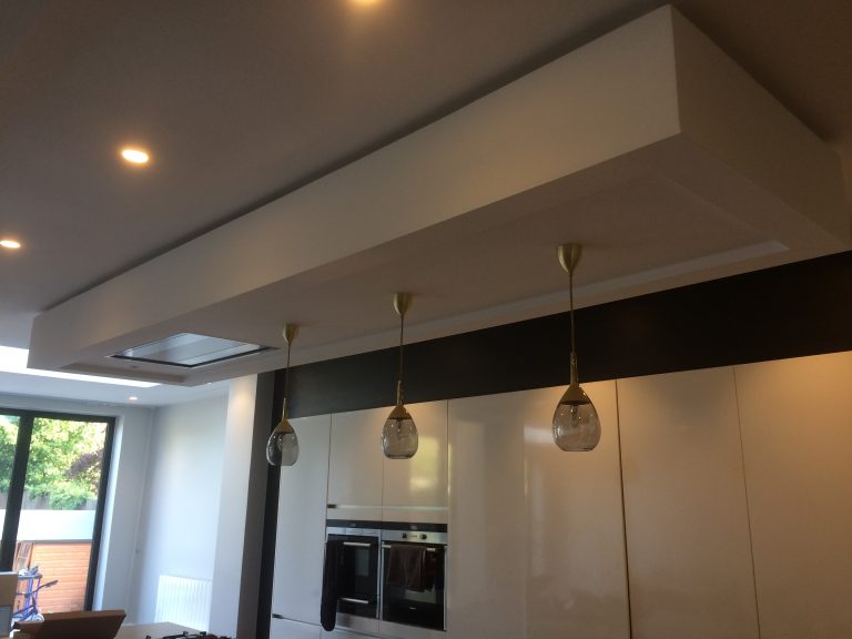 Sunette – A modern kitchen ceiling feature with three hanging glass pendant lights recessed lighting and built-in appliances below